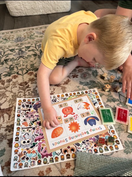 A young child sitting on the floor playing with a word puzzle