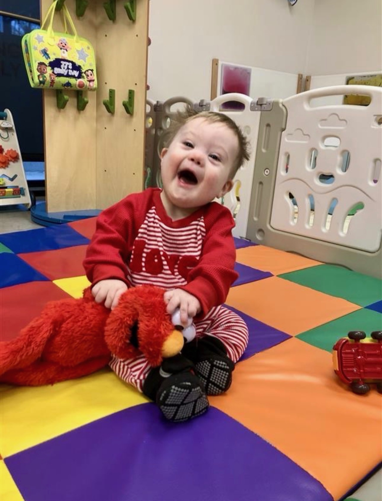 A young child sitting on the floor holding a stuffed animal